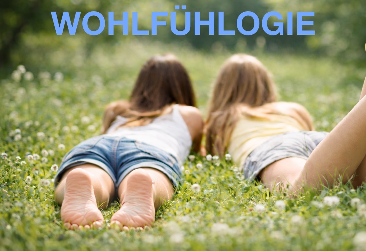 Zwei Frauen liegen barfuß im Gras in der Natur, entspannte Füße im Fokus, Symbol für Nervensystem-Regulation, Erdung und innere Balance